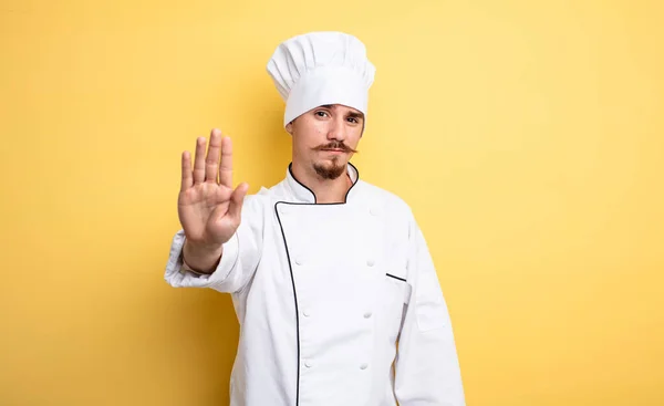厨师看上去很严肃 露出了张开手掌的姿势 — 图库照片