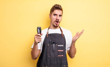 Hipster berber şaşırmış ve şok olmuş görünüyor, çenesi düşmüş bir nesne tutuyor.