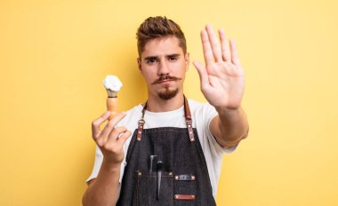 Hipster berber ciddi görünüyor. Avuç içini gösteriyor. Durdurma hareketi yapıyor.