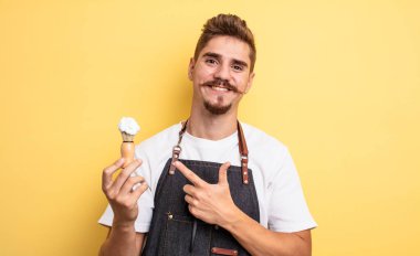 Hipster berber neşeli bir şekilde gülümsüyor, mutlu hissediyor ve bir tarafı işaret ediyor.