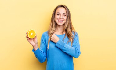 pretty woman feeling happy and facing a challenge or celebrating holding half orange