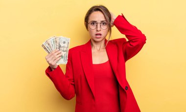 pretty woman feeling stressed, anxious or scared, with hands on head. business and dollar banknotes concept