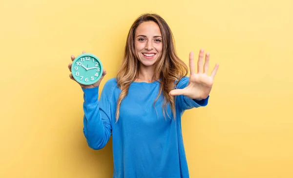 Pretty Woman Smiling Looking Friendly Showing Number Five Holding Alarm — Foto de Stock