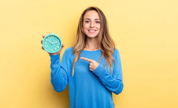 Pretty Woman Smiling Cheerfully Feeling Happy Pointing Side Holding Alarm — Stockfoto