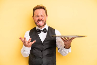 Orta yaşlı bir adam sinirli, sinirli ve sinirli görünüyor. tepsiyle garson konsepti