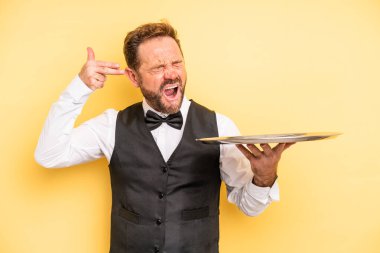 middle age man looking unhappy and stressed, suicide gesture making gun sign. waiter concept with tray