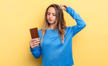 pretty woman feeling puzzled and confused, scratching head. chocolate concept