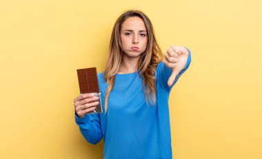 pretty woman feeling cross,showing thumbs down. chocolate concept