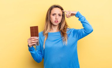 pretty woman feeling confused and puzzled, showing you are insane. chocolate concept