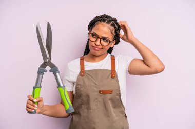 Kafası karışmış, kafası karışmış, kaşınan siyah afro bir kadın. Bahçıvan ya da çiftçi konsepti