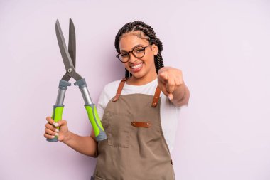 Siyah afro kadın seni seçen kamerayı işaret ediyor. Bahçıvan ya da çiftçi konsepti