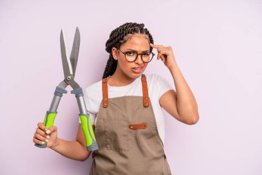 Siyah afro kadın şaşkın ve şaşkın hissediyor, senin deli olduğunu gösteriyor. Bahçıvan ya da çiftçi konsepti