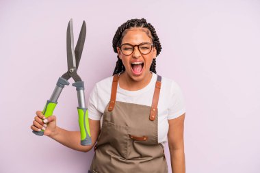 Siyah afro kadın saldırganca bağırıyor, çok kızgın görünüyor. Bahçıvan ya da çiftçi konsepti