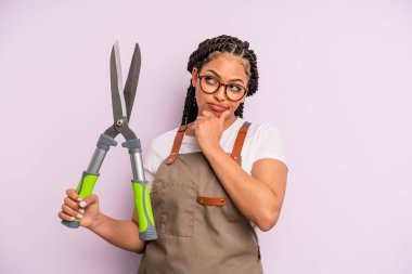 Siyah afro kadın düşünüyor, kuşkulu ve şaşkın hissediyor. Bahçıvan ya da çiftçi konsepti