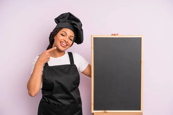 黒人アフロの女性は自信を持って笑顔を見せる シェフと黒板のコンセプト — ストック写真