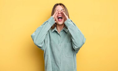 Güzel, beyaz bir kadın mutlu, heyecanlı ve pozitif hissediyor, elleri ağızlarının yanında bağırıyor, bağırıyor