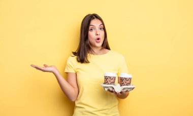 pretty woman looking surprised and shocked, with jaw dropped holding an object. take away coffee concept