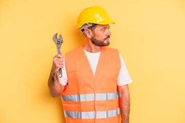 middle age man on profile view thinking, imagining or daydreaming.  breakdown car repair wrench concept