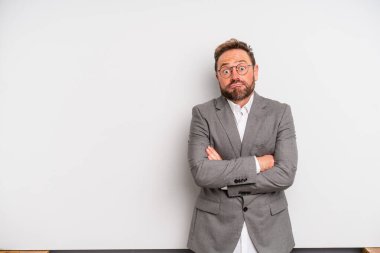 middle age man shrugging, feeling confused and uncertain. businessman concept