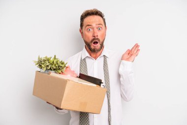 middle age man looking surprised and shocked, with jaw dropped holding an object. unemployment concept