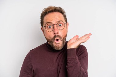middle age man looking surprised and shocked, with jaw dropped holding an object