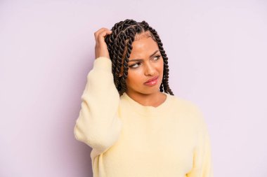 Siyah afro kadın mutlu bir şekilde gülümsüyor ve hayal kuruyor ya da şüphe ediyor