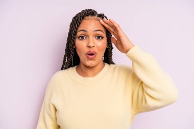 Siyah afro kadın mutlu, şaşkın ve şaşkın görünüyor.