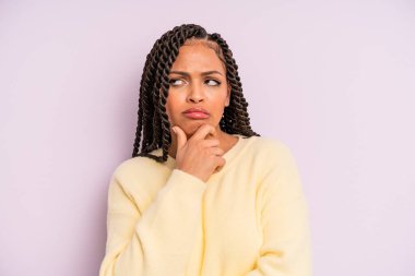 Siyah afro kadın düşünüyor, kuşkulu ve şaşkın hissediyor.