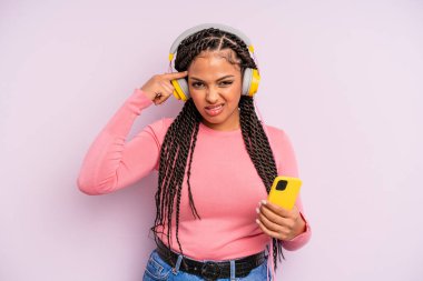 Siyah afro kadın şaşkın ve şaşkın hissediyor, senin deli olduğunu gösteriyor. müzik konseptini dinlemek