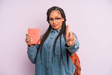 Siyah afro kadın gururla gülümsüyor ve kendinden emin bir numara oluyor. Öğrenci takvimi veya ajanda kavramı