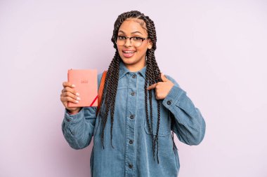 Siyah afro kadın mutlu hissediyor ve heyecanla kendini işaret ediyor. Öğrenci takvimi veya ajanda kavramı