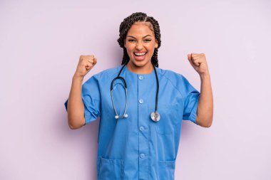 Siyah afro kadın şokta, gülüyor ve başarıyı kutluyor. hemşire konsepti