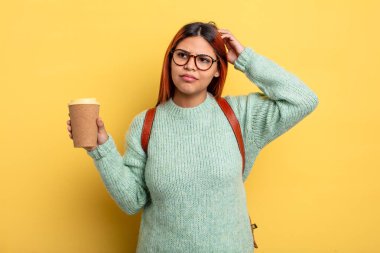 İspanyol kadın mutlu bir şekilde gülümsüyor ve hayal kuruyor ya da şüphe ediyor. Kahve konsepti olan bir öğrenci