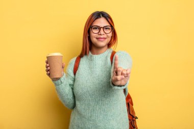 Hispanik kadın gururla gülümsüyor ve kendinden emin bir numara oluyor. Kahve konsepti olan bir öğrenci