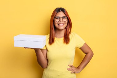 İspanyol kadın mutlu bir şekilde gülümsüyor, eli kalçasında ve kendinden emin. boş ambalaj kavramı