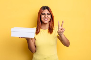 İspanyol kadın gülümsüyor ve mutlu görünüyor, zafer ya da barış işareti yapıyor. boş ambalaj kavramı