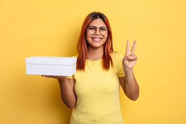 İspanyol kadın gülümsüyor ve arkadaş canlısı görünüyor, iki numarayı gösteriyor. boş ambalaj kavramı