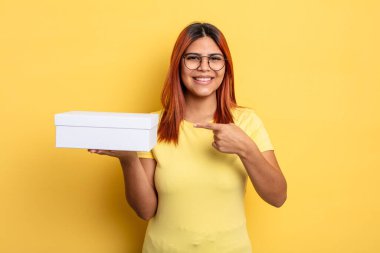 İspanyol kadın neşeyle gülümsüyor, mutlu hissediyor ve bir tarafı işaret ediyor. boş ambalaj kavramı