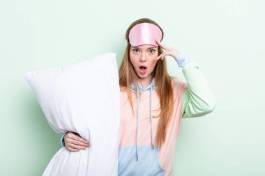 Kızıl saçlı kadın şaşırmış görünüyor, yeni bir düşünce, fikir ya da konsept keşfediyor. Pijama ve yastık konsepti