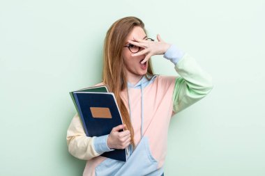 Kızıl saçlı kadın şok olmuş, korkmuş ya da dehşete düşmüş gibi görünüyor, yüzünü eliyle kapatıyor. öğrenci konsepti