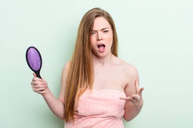 Kızıl saçlı kadın sinirli, sinirli ve sinirli görünüyor. saç tarağı konsepti