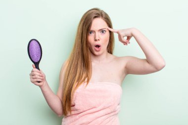 Kızıl saçlı kadın şaşırmış görünüyor, yeni bir düşünce, fikir ya da konsept keşfediyor. saç tarağı konsepti