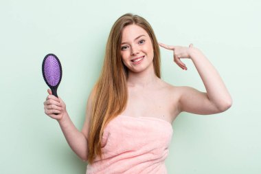 Kızıl saçlı kadın kendi gülüşünü işaret ederek kendine güler. saç tarağı konsepti