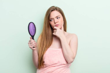 Kızıl saçlı kadın düşünüyor, kuşkulu ve şaşkın hissediyor. saç tarağı konsepti