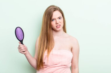 Kızıl saçlı kadın şaşkın ve şaşkın hissediyor. saç tarağı konsepti