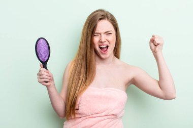 Kızıl saçlı kadın kızgın bir ifadeyle agresif bir şekilde bağırıyor. saç tarağı konsepti