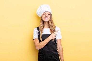 pretty woman smiling cheerfully, feeling happy and pointing to the side. chef concept