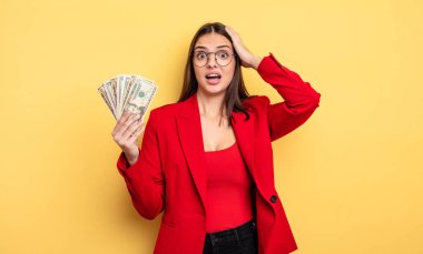 pretty woman feeling stressed, anxious or scared, with hands on head. dollar banknotes concept