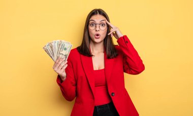 pretty woman looking surprised, realizing a new thought, idea or concept. dollar banknotes concept
