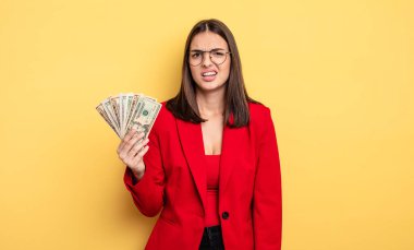 pretty woman feeling puzzled and confused. dollar banknotes concept